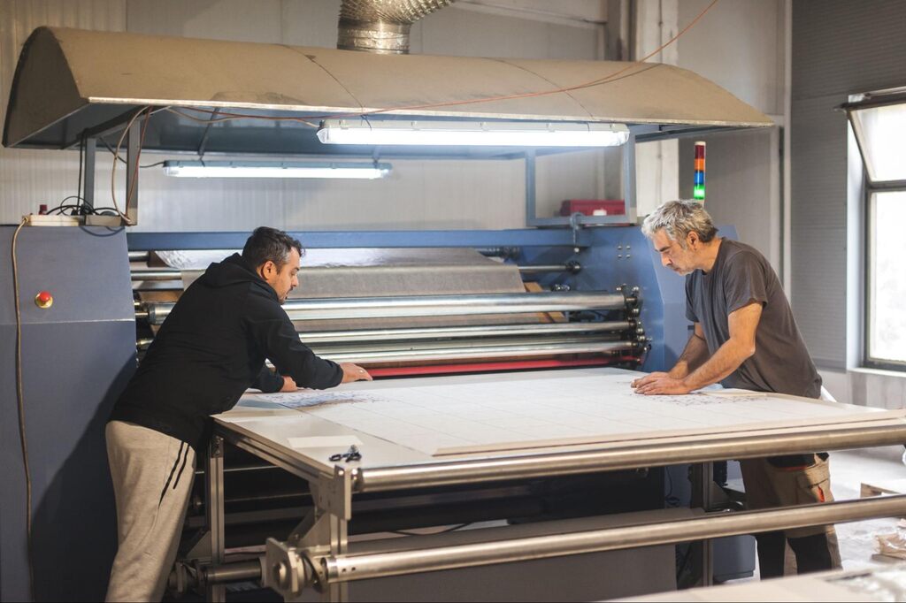 Pessoas trabalhando com papéis para sublimação na máquina